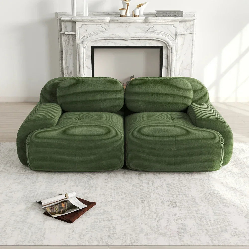 Modern green corduroy sofa in front of a white marble fireplace on a light area rug