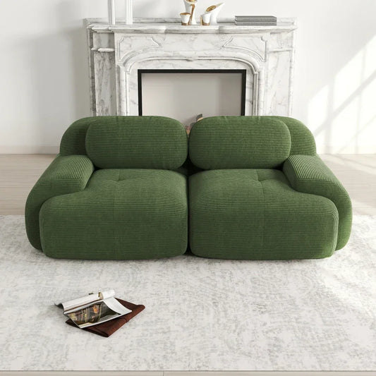 Modern green corduroy sofa in front of a white marble fireplace on a light area rug